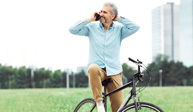 An older man wearing chinos and a shirt on a bike