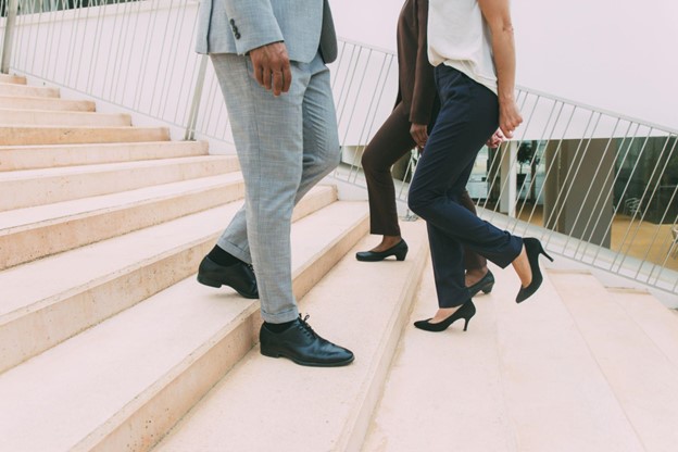 A man and two women cross paths on stone steps, each wearing dress shoes.