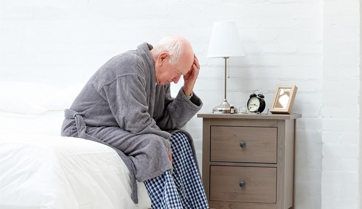 A man in his seventies struggling to sleep in a cold room.