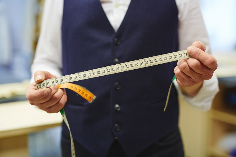 A man holds a fabric tape measure that will be used to measure chest size.