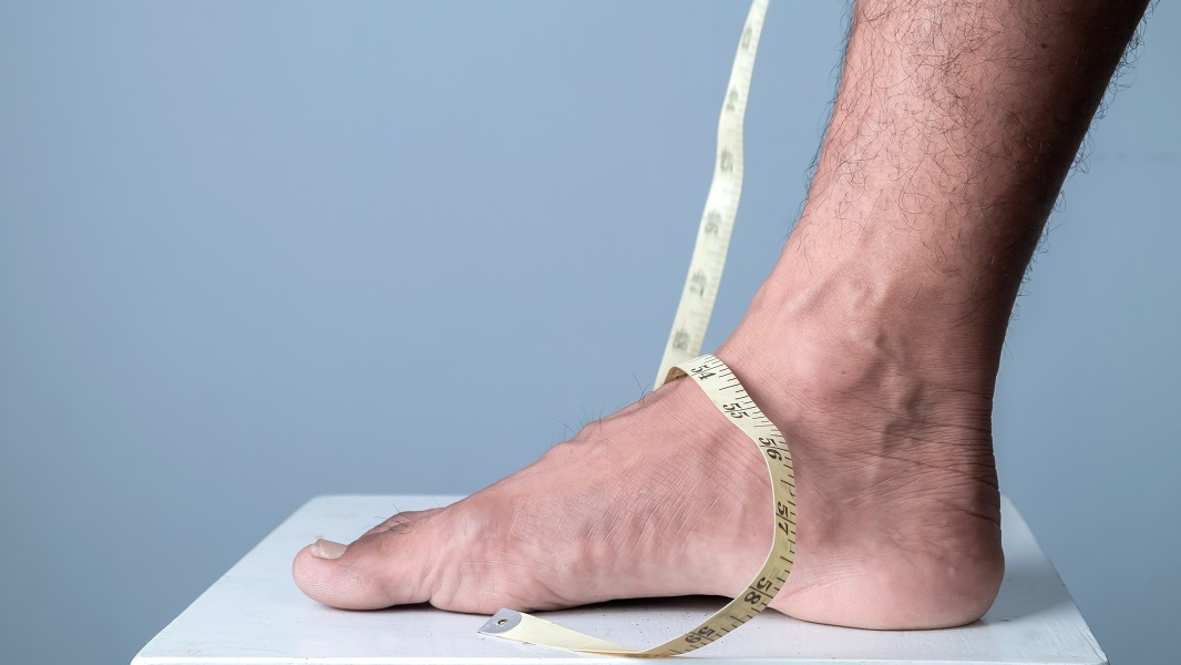 A man preparing to use a fabric tape measure to measure his foot.