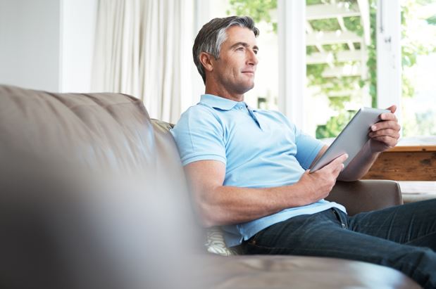 Older man wearing a blue polo shirt relaxing on the sofa