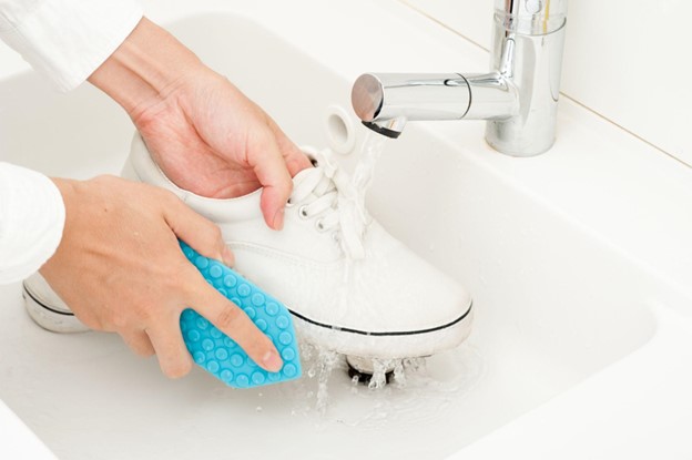 A woman hand washing a pair of trainers