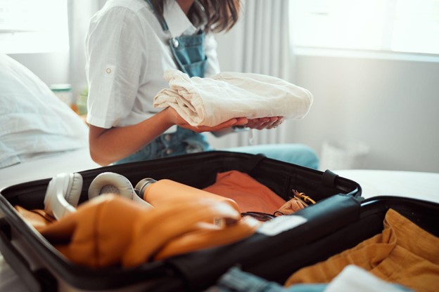 A woman choosing clothes to pack in a suitcase before a holiday.