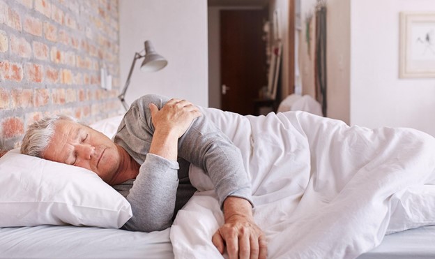 An older man supporting his back by sleeping on his side.